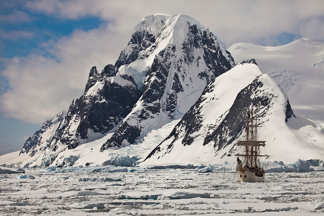 Rigged tourist ship Europa in heavy pack ice beneath Mount Scott, Penola Strait, Antarctic Peninsula, Antarctica