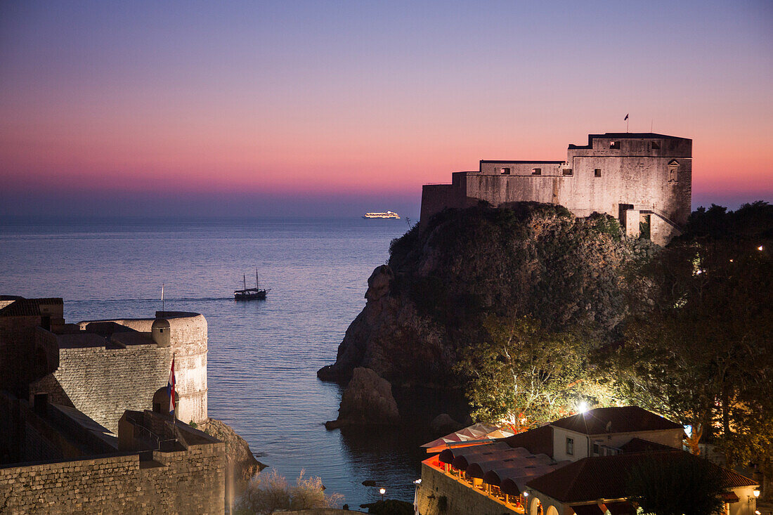 Blick von der Stadtmauer auf Festung und Ausflugsboot in der Abenddämmerung, Dubrovnik, Dalmatien, Kroatien, Europa