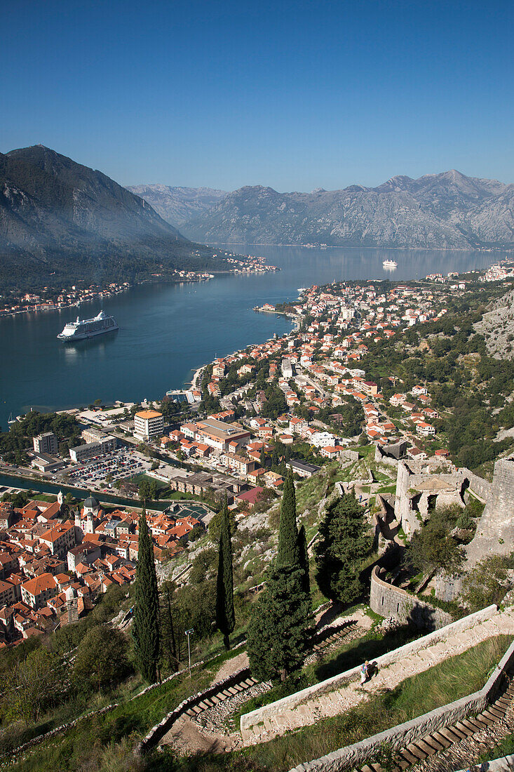 Steep walkway to fortress and view over Old Town and cruise ships Seven Seas Voyager, Regent Cruises, and MS Deutschland, Reederei Peter Deilmann, in Kotor Fjord, Kotor, Montenegro