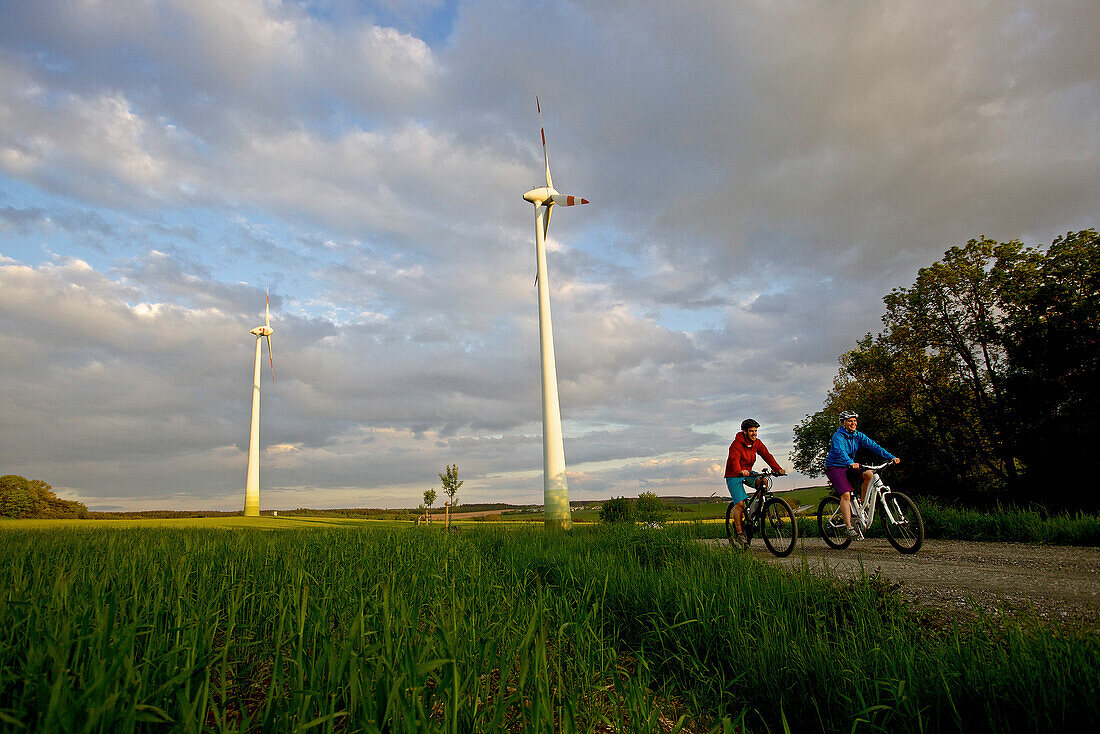 Two cyclists riding electric bicycles between fields, Tanna, Thuringia, Germany