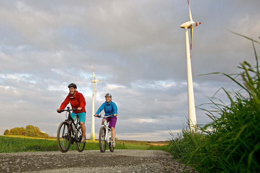 Zwei Fahrradfahrer fahren mit Elektrofahrrädern zwischen Feldern, Tanna, Thüringen, Deutschland