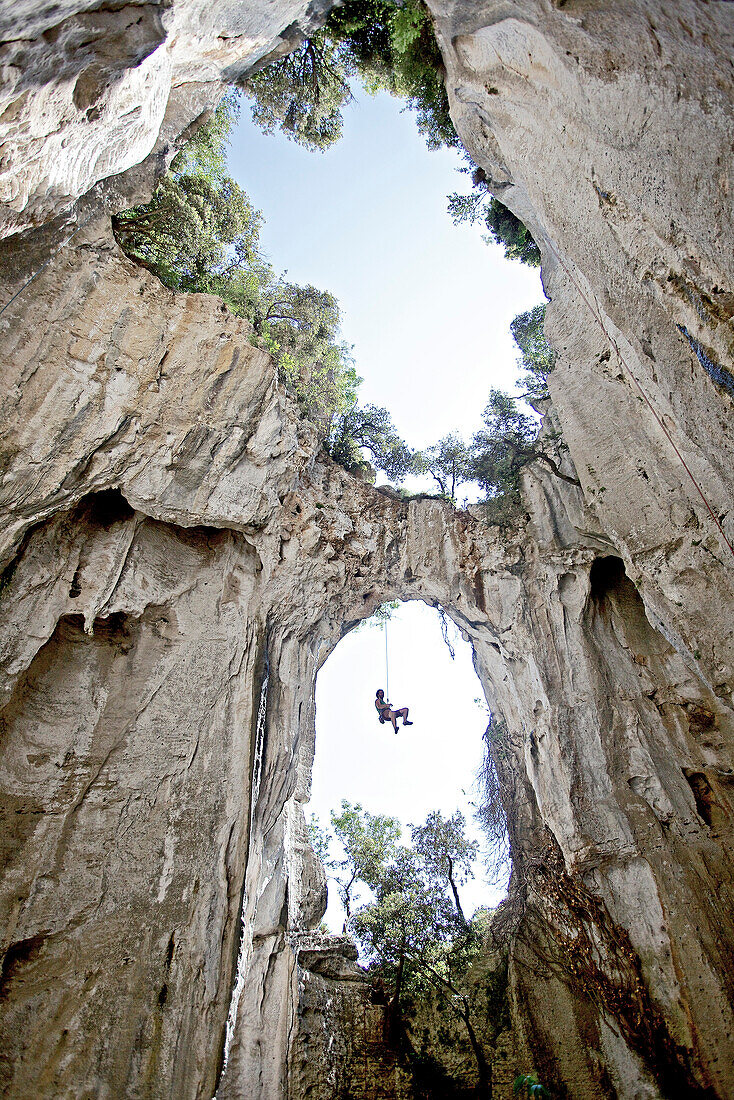 Kletterer hängt unter einem Felsbogen an einem Seil, Finale Ligure, Provinz Savona, Ligurien, Italien