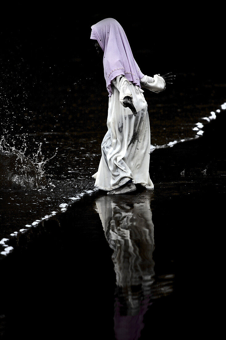 Girl wearing traditional clothes standing in water at beach, Jakarta, Java, Indonesia