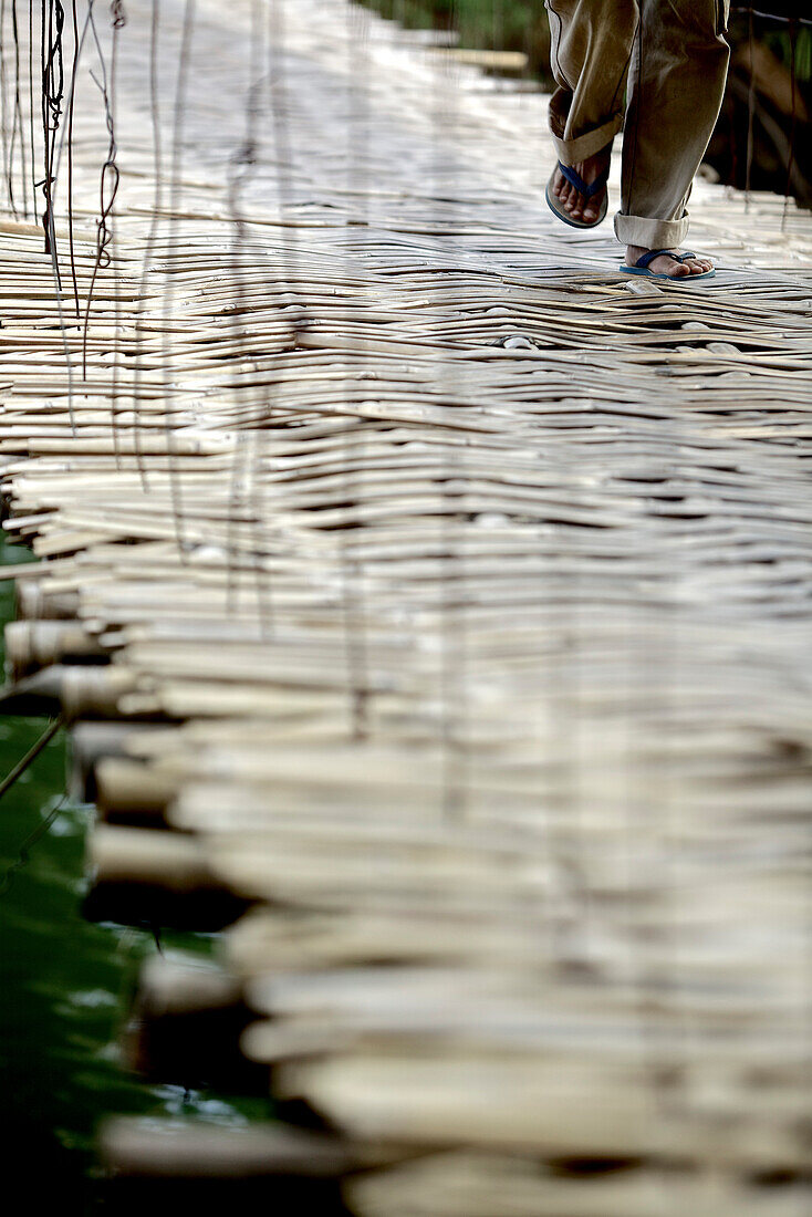 Mann läuft über eine einfache Bambusbrücke, Denpasar, Bali, Indonesien