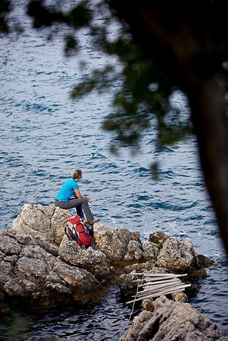 Frau rastet auf einem Felsen, Fernwanderweg Lykischer Weg, Antalya, Türkei
