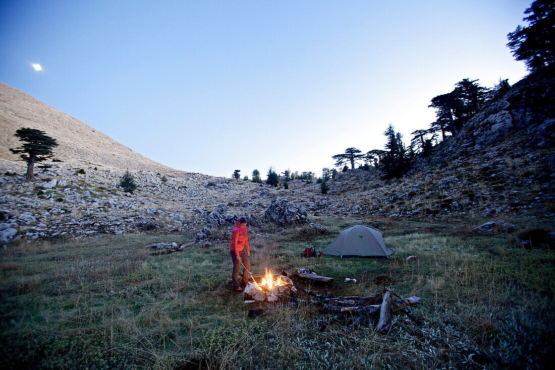 Woman standing at a campfire, long-distance footpath Lycian Way, Antalya, Turkey