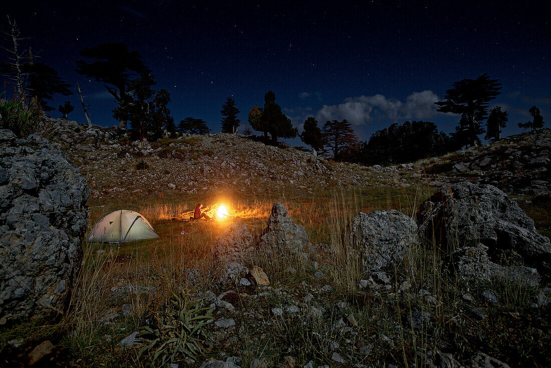 Woman sitting at a campfire in the evening, long-distance footpath Lycian Way, Antalya, Turkey