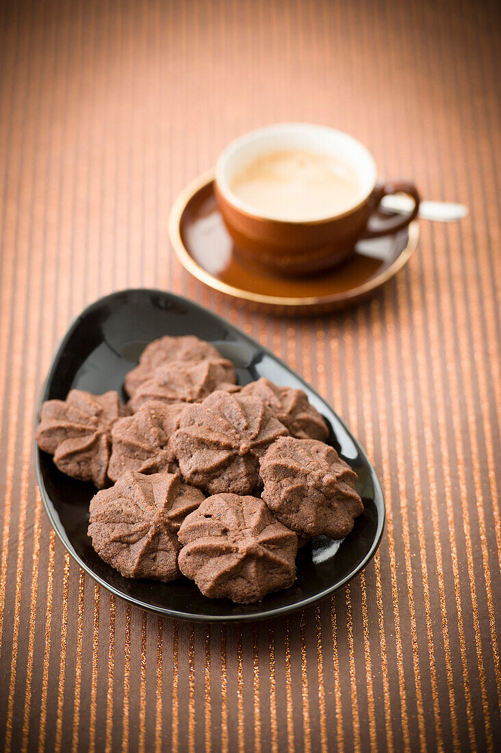 A cup of espresso and a dish of cookies