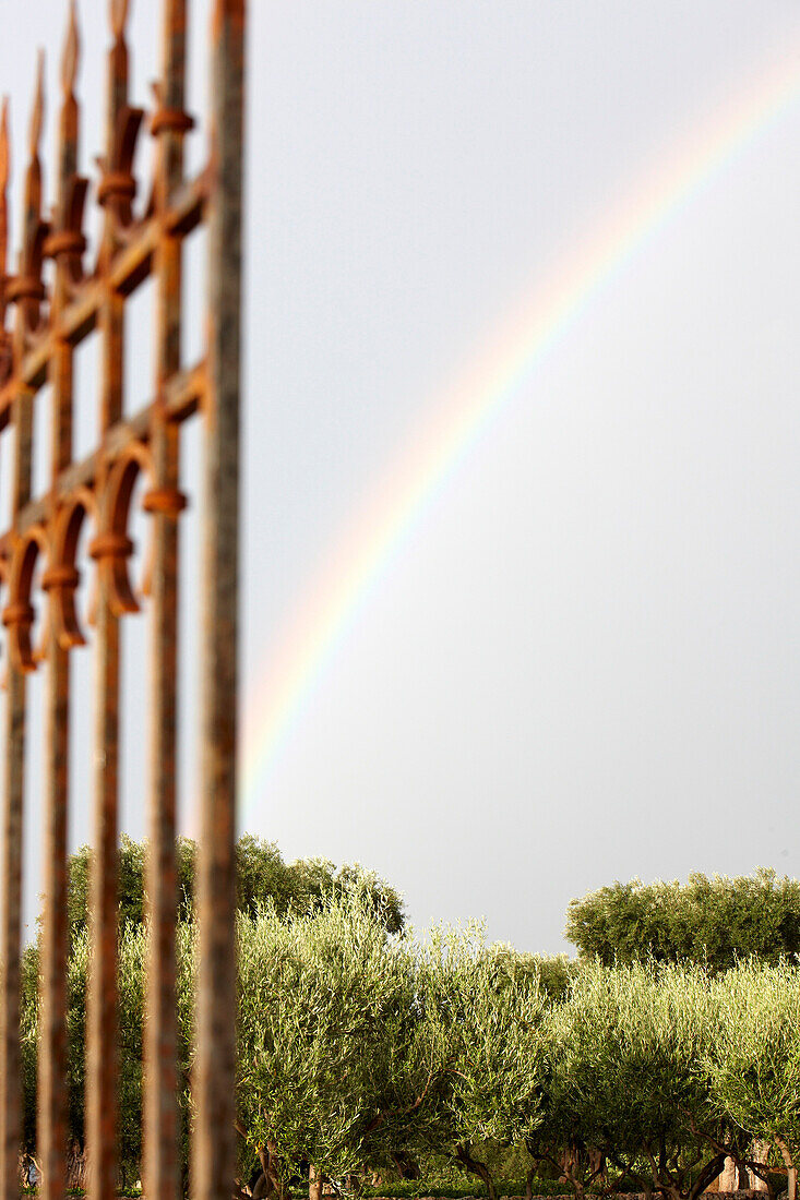 View through a garden gate towards a rainbow, Masseria, Alchimia, Apulia, Italy