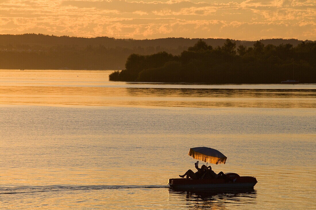 Person reading a book on a boat at sunset, Ammersee, Upper Bavaria, Bavaria, Germany