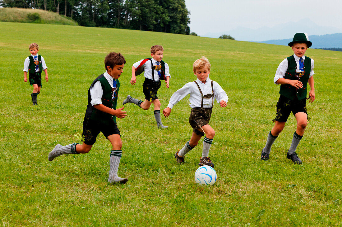 Kids in traditional bavarian dress playing football, Jasberg, Dietramszell, Upper Bavaria, Bavaria, Germany