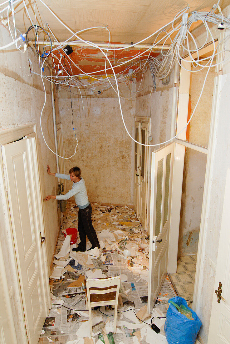 Woman removing wallpaper in a flat, Leipzig, Saxony, Germany