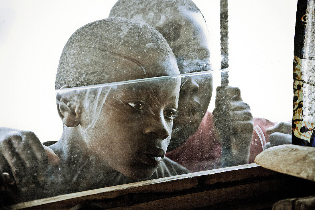 Zwei Buben schauen durch ein Fenster, Malawi, Afrika