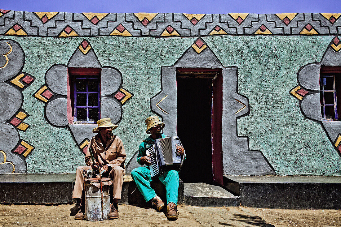 Zwei Männer vom Bergvolk der Basotho musizieren vor einer Hauswand mit traditioneller Fassadenmalerei, Südafrika, Afrika