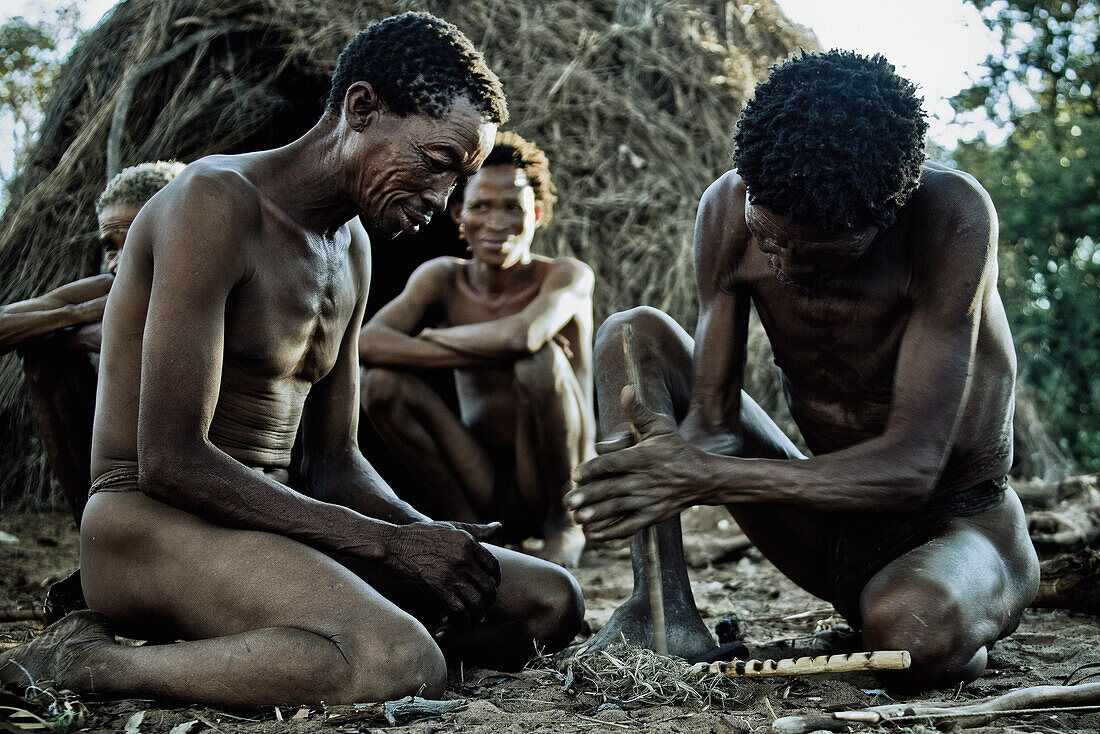 Men from the San tribe igniting a fire with two wooden sticks, Otjozondjupa region, Namibia, Africa