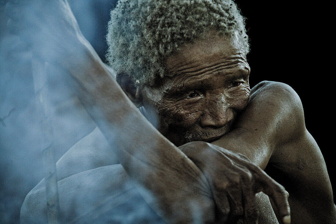 Alter Mann der San Volksgruppe sitzen am Lagerfeuer, Region Otjozondjupa, Namibia, Afrika
