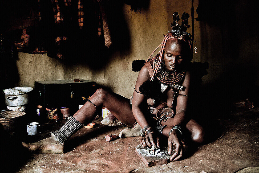 Woman of the Himba tribe in her hut preparing food, Kaokoland, Namibia, Africa