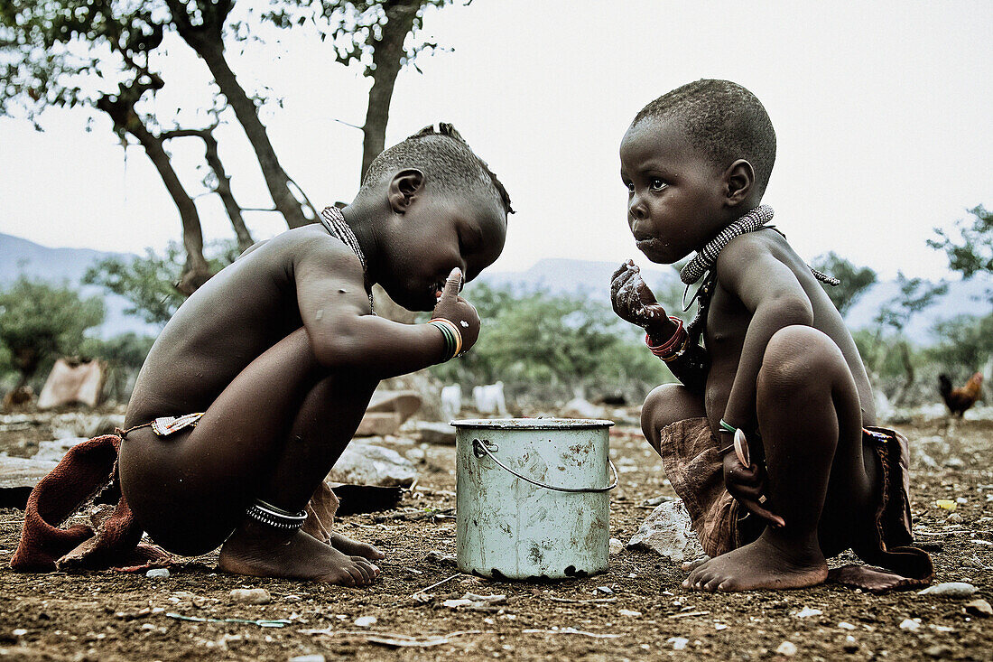 Two children of the Himba tribe eating out of a pot, Kaokoland, Namibia, Africa