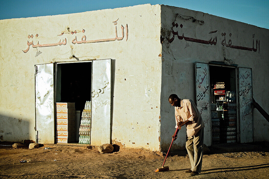 Ein Mann fegt die Straße vor seinem Ladengeschäft, Wadi Halfa, Sudan, Afrika
