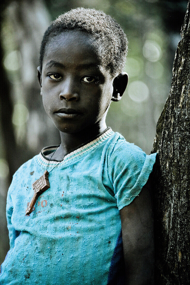 Junge der Konzo-Volksgruppe lenht an einen Baum, Südäthiopien, Afrika
