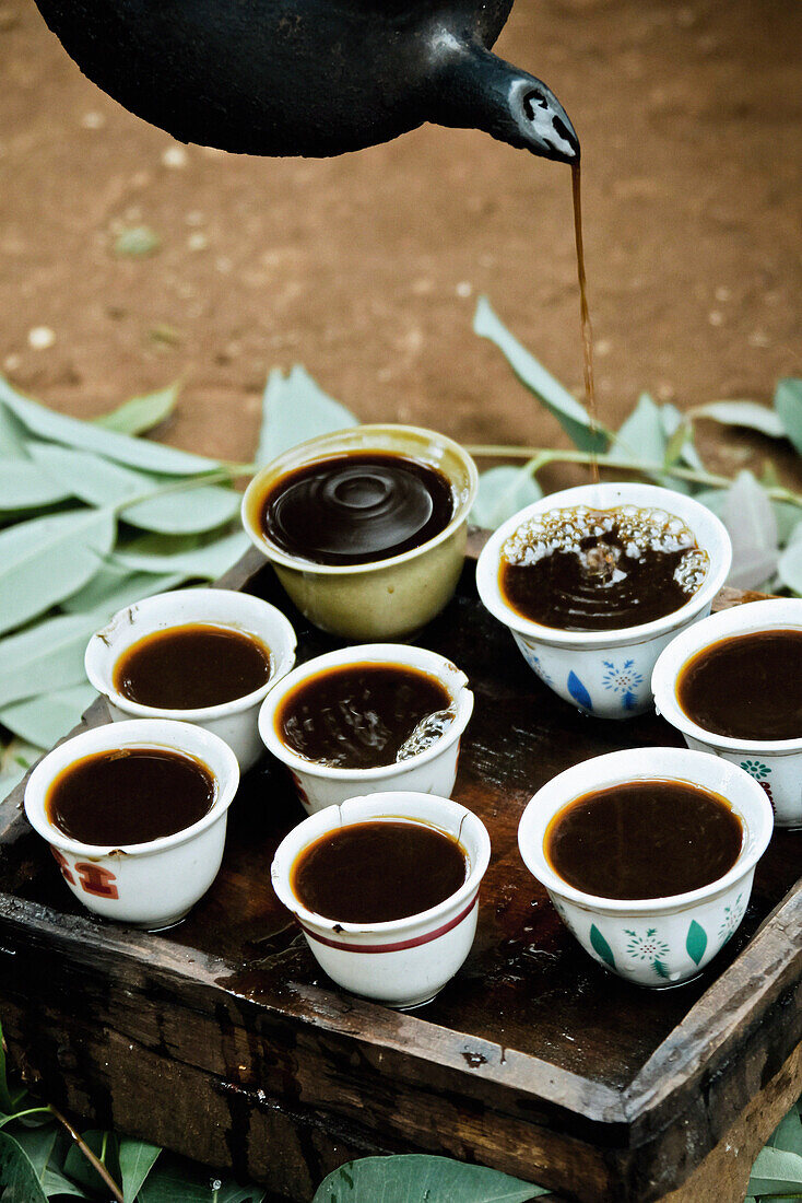 Aus einer Tonkanne wird frischgebrühter Kaffee in Tassen eingeschenkt, Äthiopien, Afrika