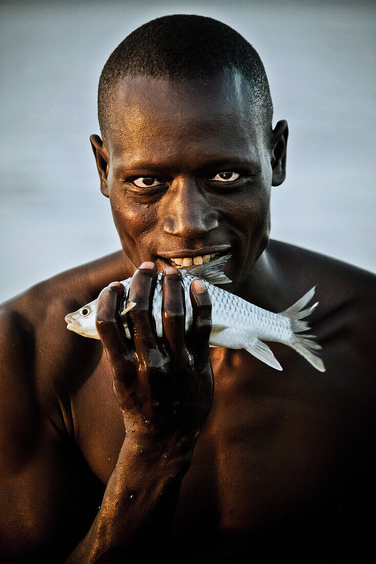 A fisherman from the Njemps tribe holding a fish, Lake Baringo, Kenya, Africa