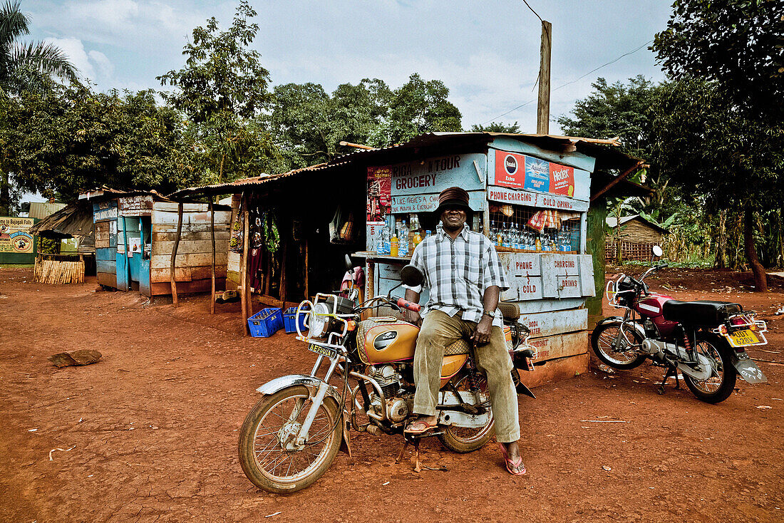 Taxifahrer mit seinem Motorradtaxi, Marktstraße in Buwenda, Uganda, Afrika