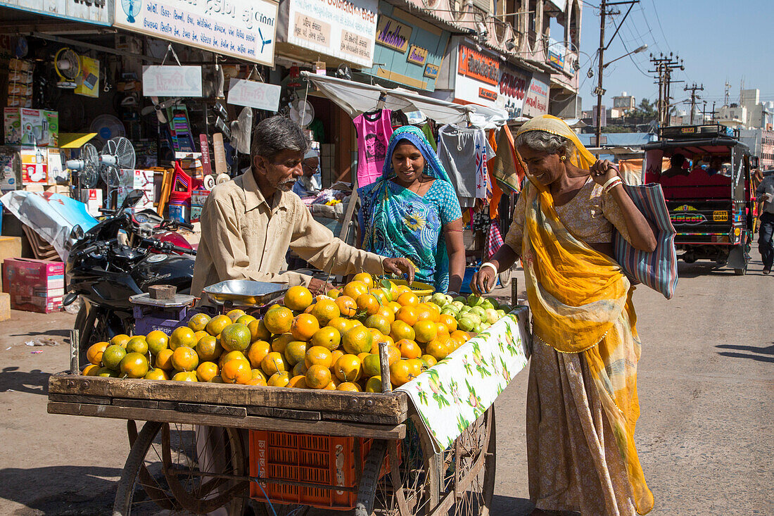Zwei Frauen an einem Fruchtstand im Stadtzentrum, Porbandar, Gujarat, Indien