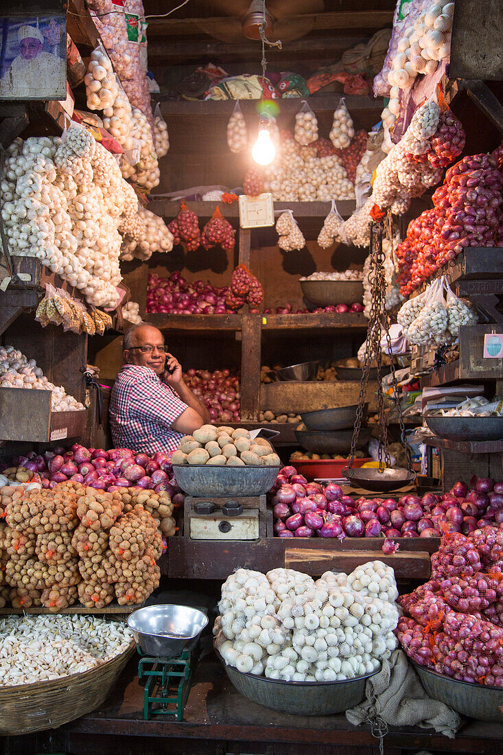 Verkäufer mit Zwiebeln und Kartoffeln an einem Marktstand im Mahatma Jyotiba Phule Market, Crawford Market, Mumbai, Maharashtra, Indien