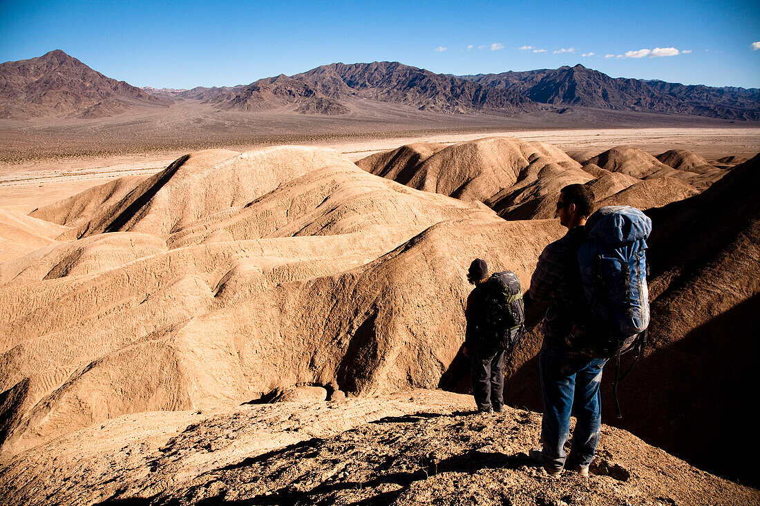 Two male hikers search to find the best route through Death Valley's Confidence Hills, in California, while on backing packing Death Valley, California, United States of America