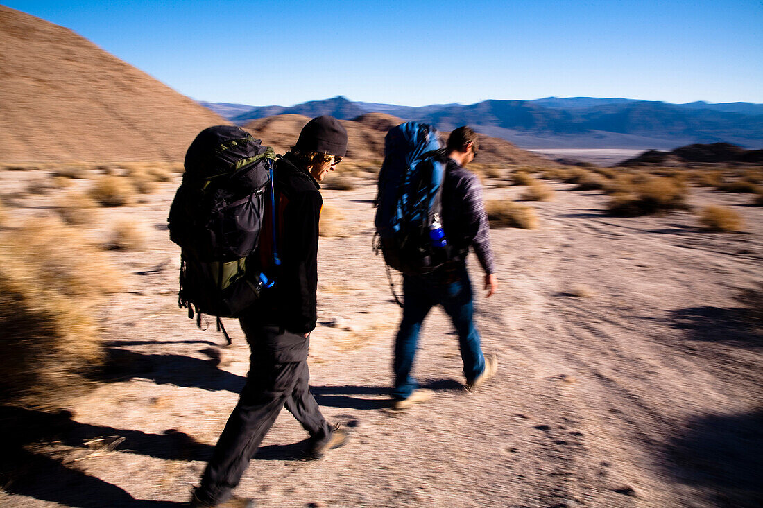 A pair of young male hikers backpack through Death Valley's Confidence Hills, California Death Valley, California, United States of America