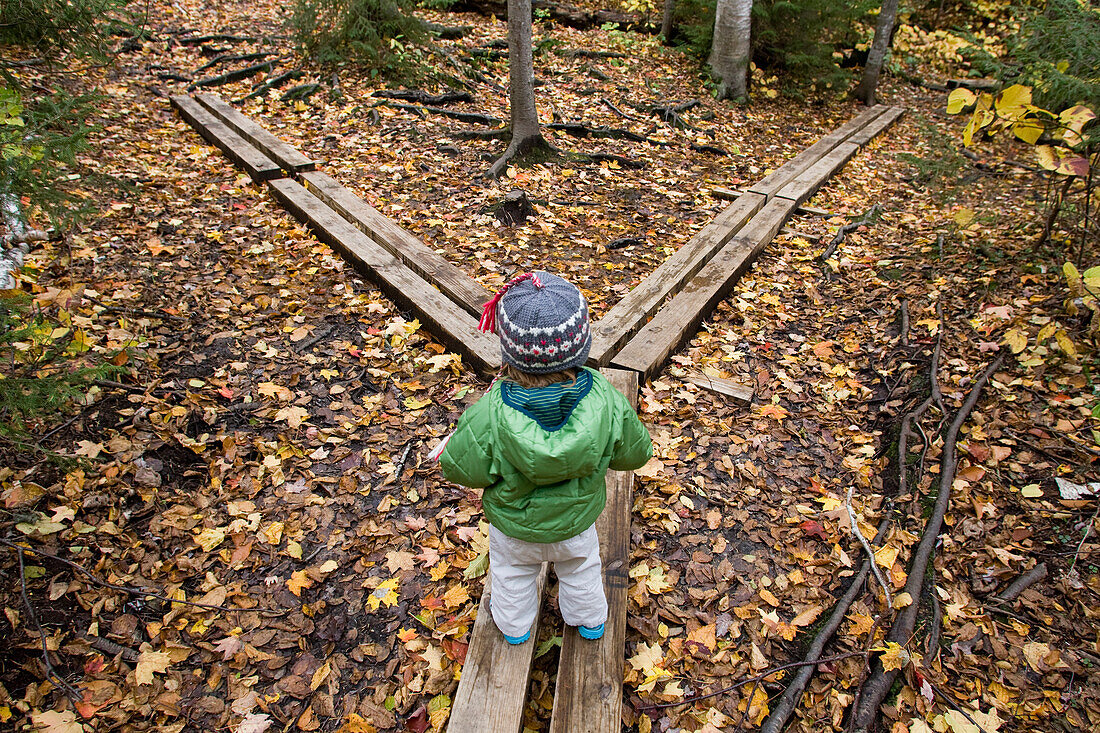 A young girl walks across hiking bridges in Grafton Notch State Park, Maine Newry, Maine, USA
