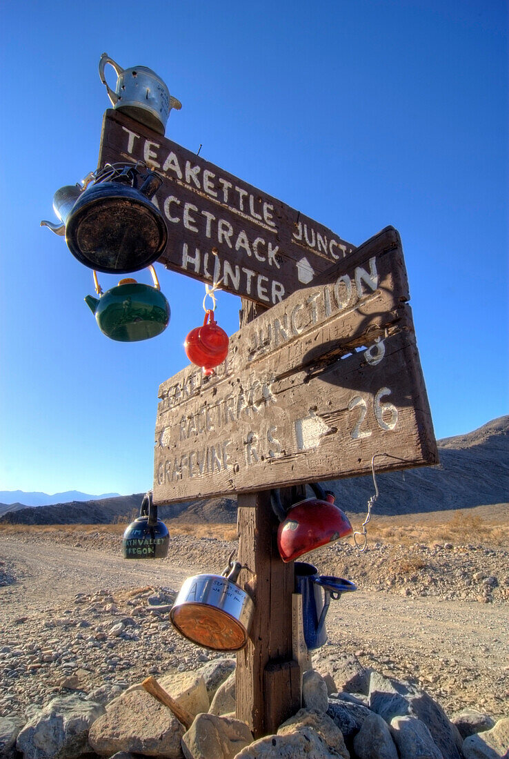 Teakettles hang on the road sign at Teakettle Junction in Death Valley National Park, California Death Valley National Park, California, USA