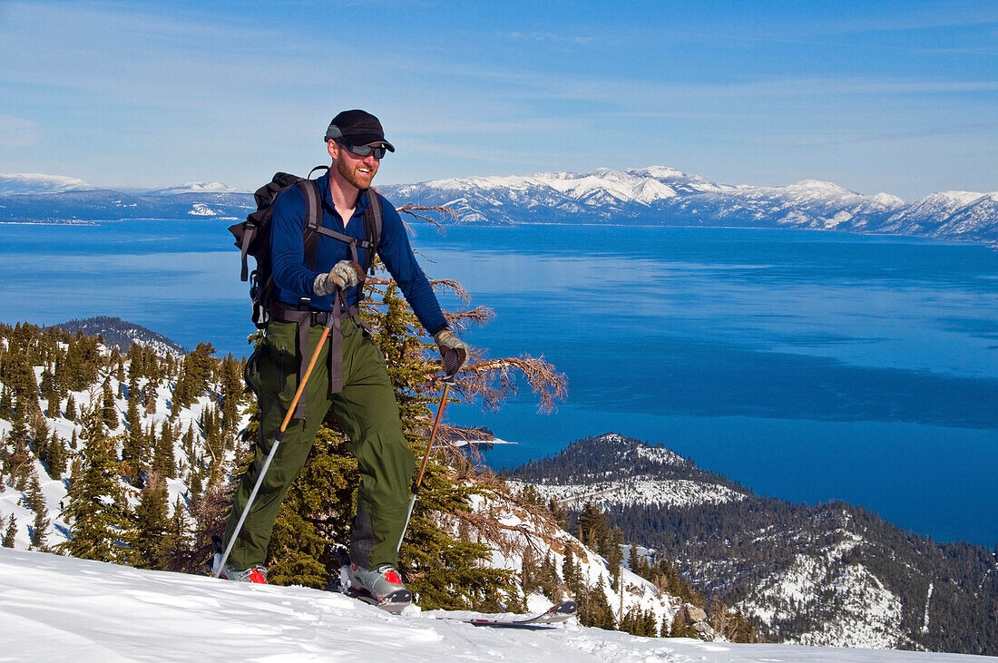 A male skier skins up Mount Tallac with Lake Tahoe in the background, CA Lake Tahoe, California, USA