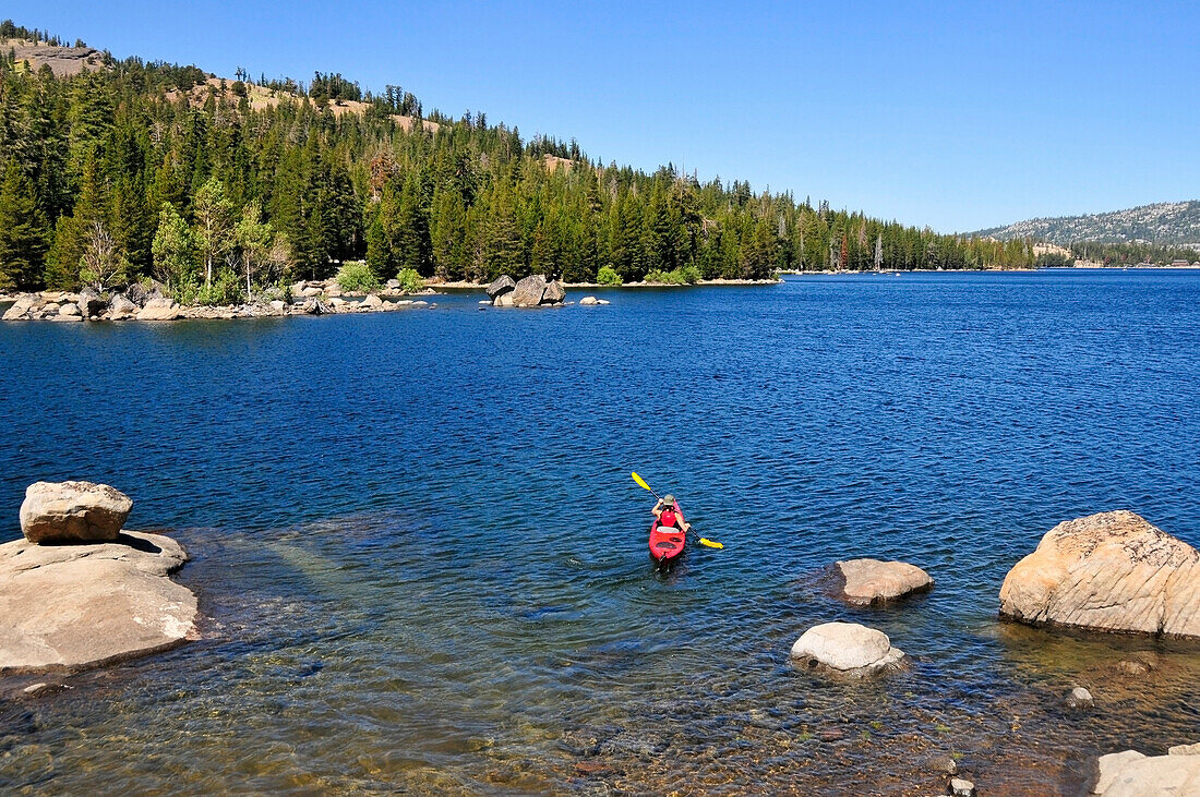 A woman kayaks on Caples Lake near Kirkwood, California in the summer Caples Lake, Sierra Nevada, California, USA