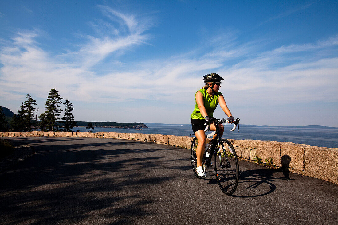 A female cyclist rides her road bike in Maine's Acadia National Park Acadia National Park, Maine, United States of America