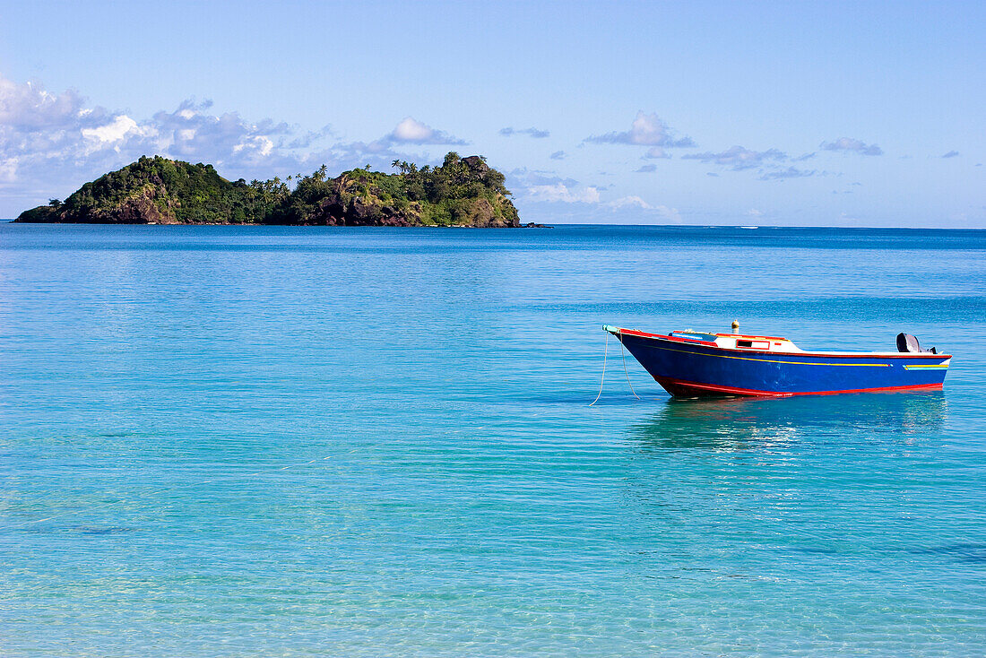 A blue wooden fishing boat floats in the calm waters of Malakati, Fiji Malakati, Nacula, Fiji