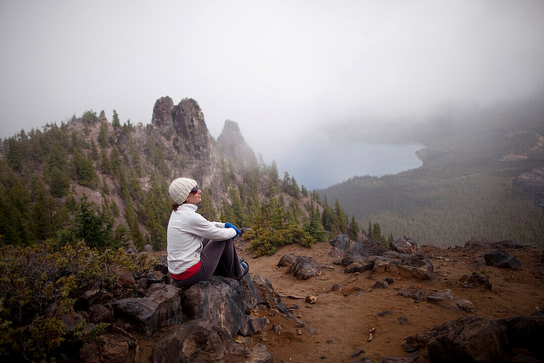 A young woman rests after hiking around the rim of Newberry Volcano east of the Cascade range near Bend, Oregon, Oregon, USA
