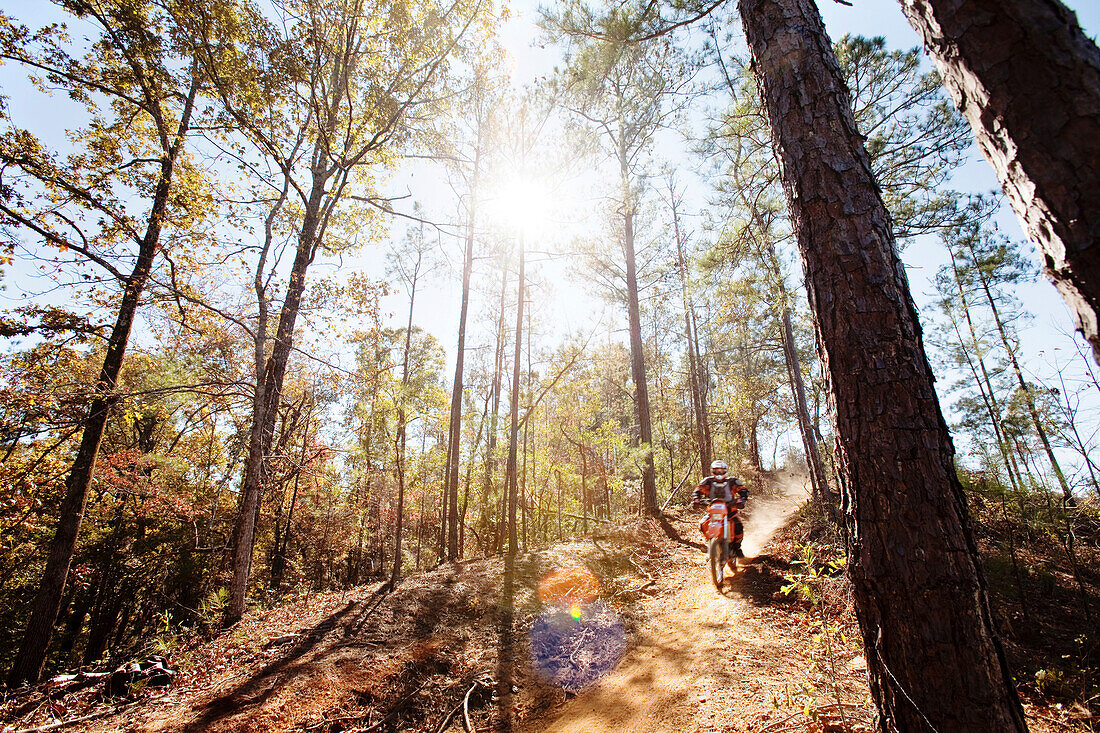 A motorcyclist rides a dirt trial on top of a hill in an Enduro race in Maplesville, Alabama. (Back Lit, Lens Flare, Motion Blur), Maplesville, Alabama, United States