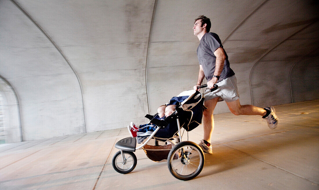 A man runs through a tunnel with his twin sons in a stroller. (Motion Blur), Helena, Alabama, United States