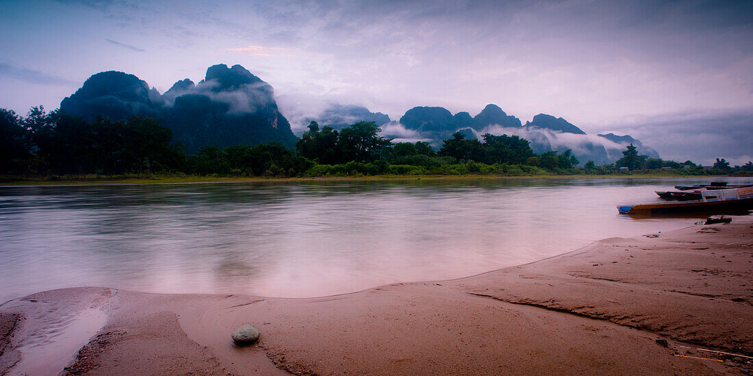 Small stone, river and mountains covered in mist.  Vang Vieng, Laos, Asia Vang Vieng, Vientiane, laos