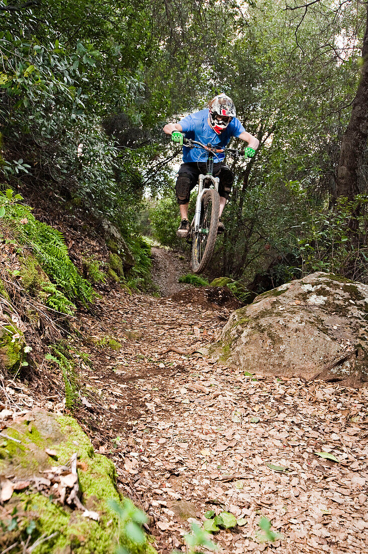 A young man rides his downhill mountain bike on Knapps Castle Trail, surrounded by beautiful scenery in Santa Barbara, CA Santa Barbara, CA, USA