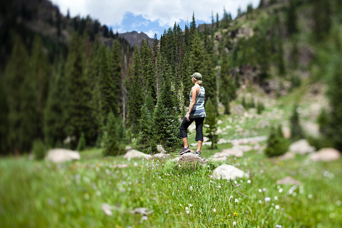 A young woman stands in a field of wildflowers taking in the view Vail, Colorado, USA
