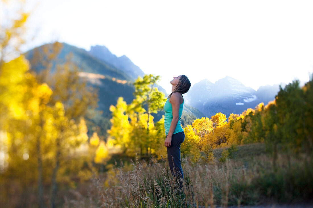 A young woman breathes deeply surrounded by gold forests and snow capped peaks Aspen, Colorado, USA