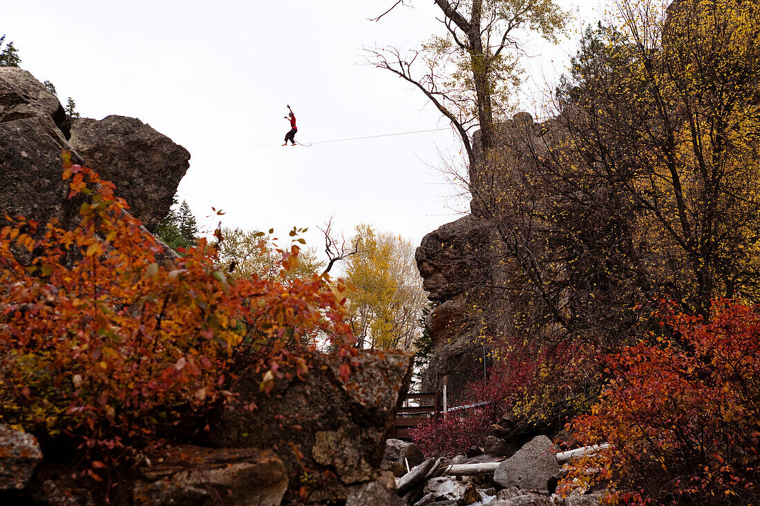 A young man walks a high line over a creek in Colorado Glenwood Springs, Colorado, USA