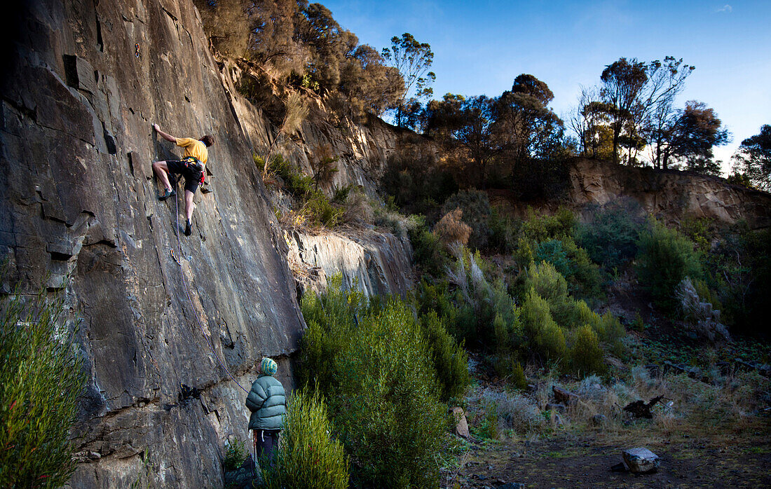 Climber in a yellow shirt leads his way up a quarry wall in Tasmania, Australia Hobart, Tasmania, Australia