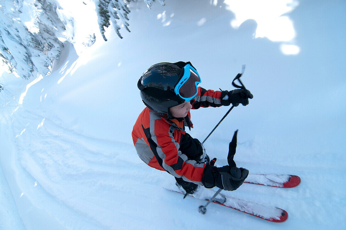 Young boy with helmet on alpine skiing on a bright sunny day White Mountains, New Hampshire, USA