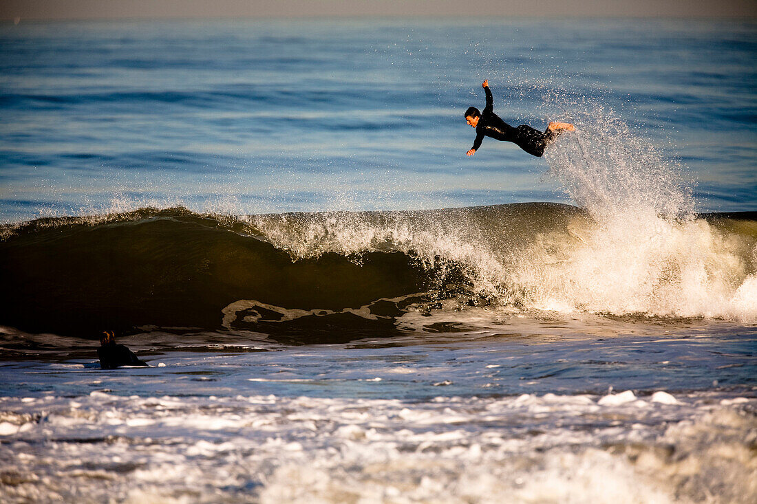 A male surfer jumps over the top of a breaking wave in Ventura, California Ventura, California, Unites States of America