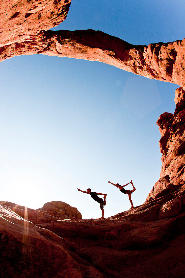 Couple doing dancer pose (yoga) under the turret arch in Arches National Park Moab, Utah, USA