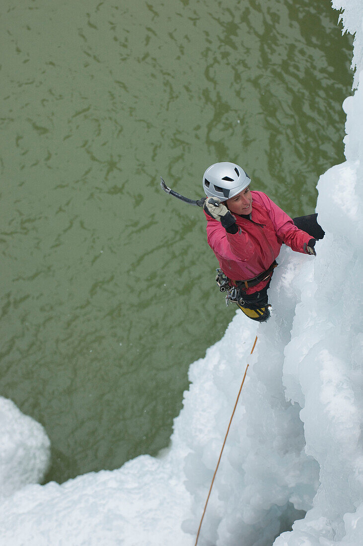 Woman climbing ice above water, Ouray, Colorado Ouray, Colorado, USA